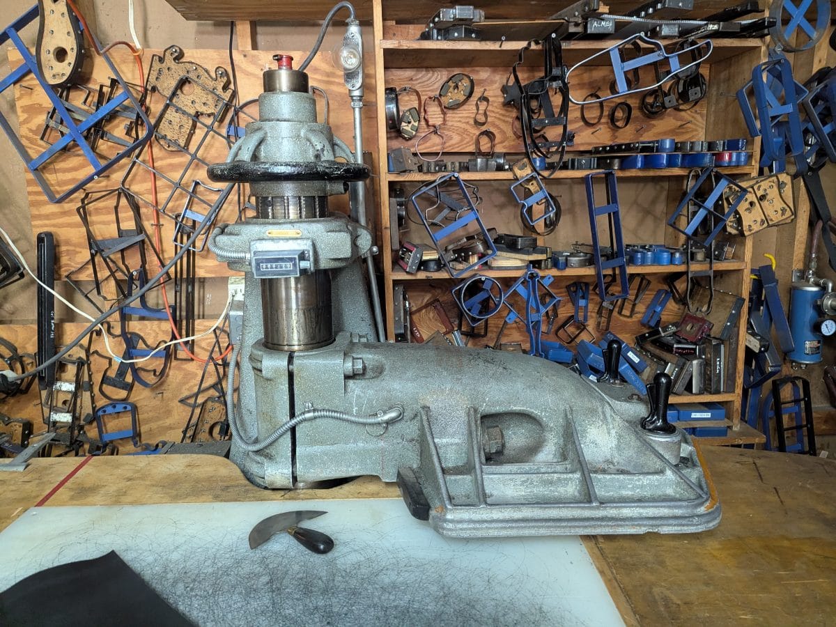 A clicker die press and racks of steel cutting dies in the Christian Workshop shop.